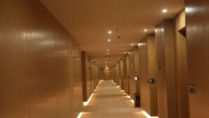 A long, narrow hallway with a carpeted floor and wooden walls, leading to multiple doors. - Star Sky Hotel (Fu County)