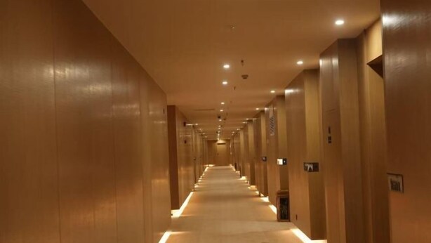 A long, narrow hallway with a carpeted floor and wooden walls, leading to multiple doors. - Star Sky Hotel (Fu County)