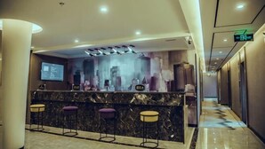 Ein Hotel-Rezeptionsbereich mit Marmor-Theke, Barhocker und einem digitalen Bildschirm, der Informationen zeigt.