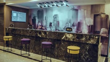A bar area with a marble countertop, purple stools, and a cityscape mural.