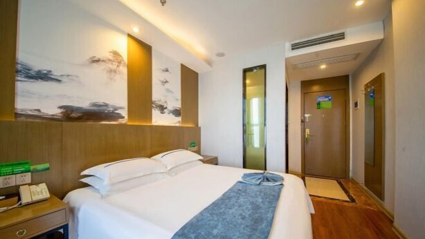 Ein Hotelzimmer mit Bett, Nachttisch und einem Wandbild.