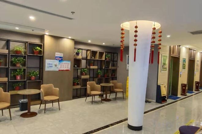 Een hotel lobby met zithoeken, een receptiebalie en een zuil met decoraties.