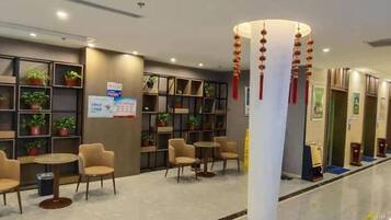 Een hotel lobby met zithoeken, een receptiebalie en een zuil met decoraties.
