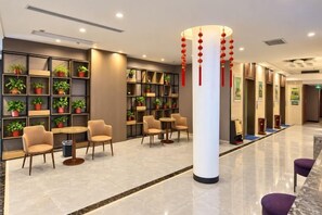 A lobby with seating areas, a reception desk, and shelves with plants.