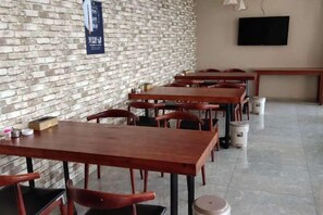 A restaurant with brick walls, wooden tables, and chairs. - Leiketai Theme Hotel (Bengbu Railway Station Branch) (Bengbu)