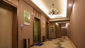Ein Hotel-Flur mit Aufzügen, Mülleimern und Teppichboden.