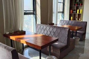 A modern hotel room with a sofa, a wooden table, and a view of the city. - Leiketai Theme Hotel (Bengbu Railway Station Branch) (Bengbu)