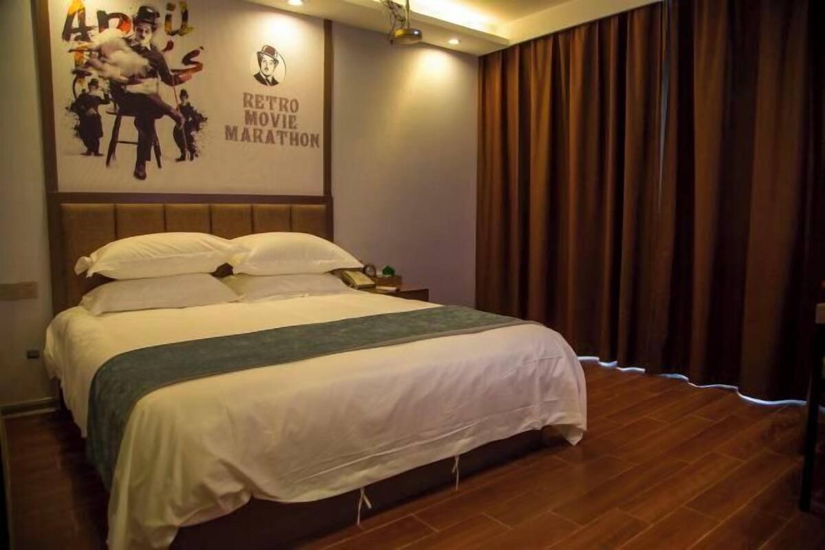 A hotel room with a large bed, a poster on the wall, and a curtain.