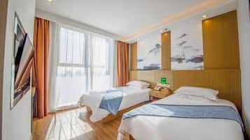 A hotel room with two beds, a large window with curtains, a painting on the wall, and a wooden floor.