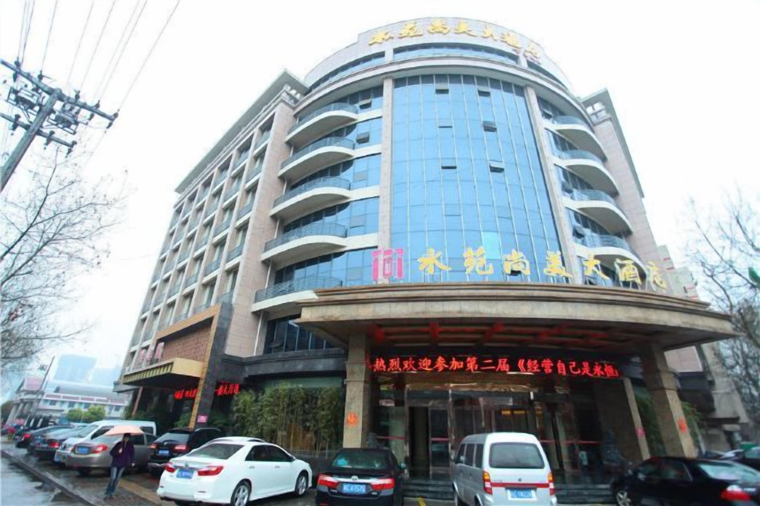 A multi-story hotel with a curved facade, multiple balconies, and a prominent entrance with signage.