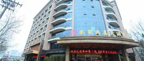 A multi-story hotel with a curved facade, multiple balconies, and a prominent entrance with signage.