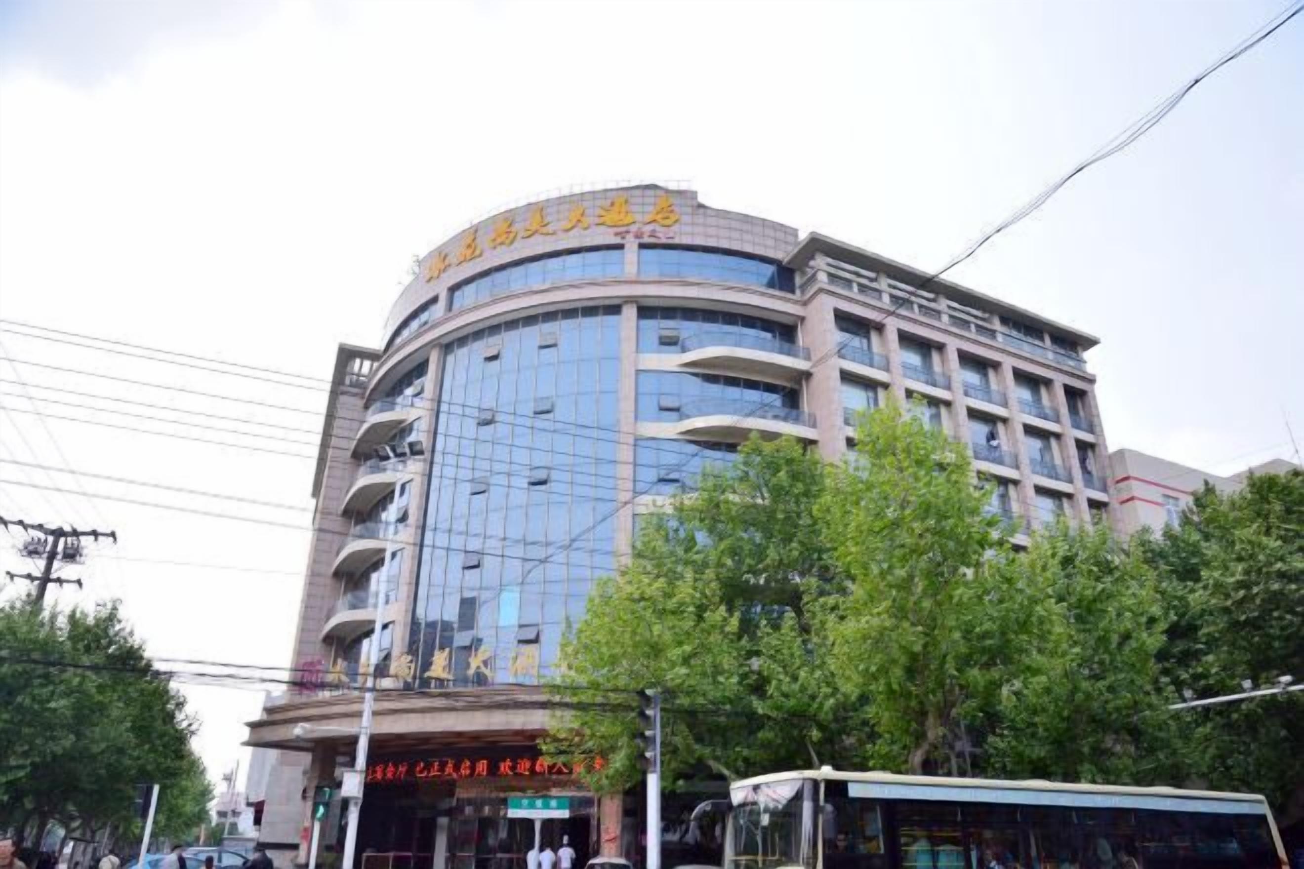 Un hôtel à plusieurs étages, doté d’une façade incurvée, de nombreux balcons et d’une entrée bien visible avec une enseigne.