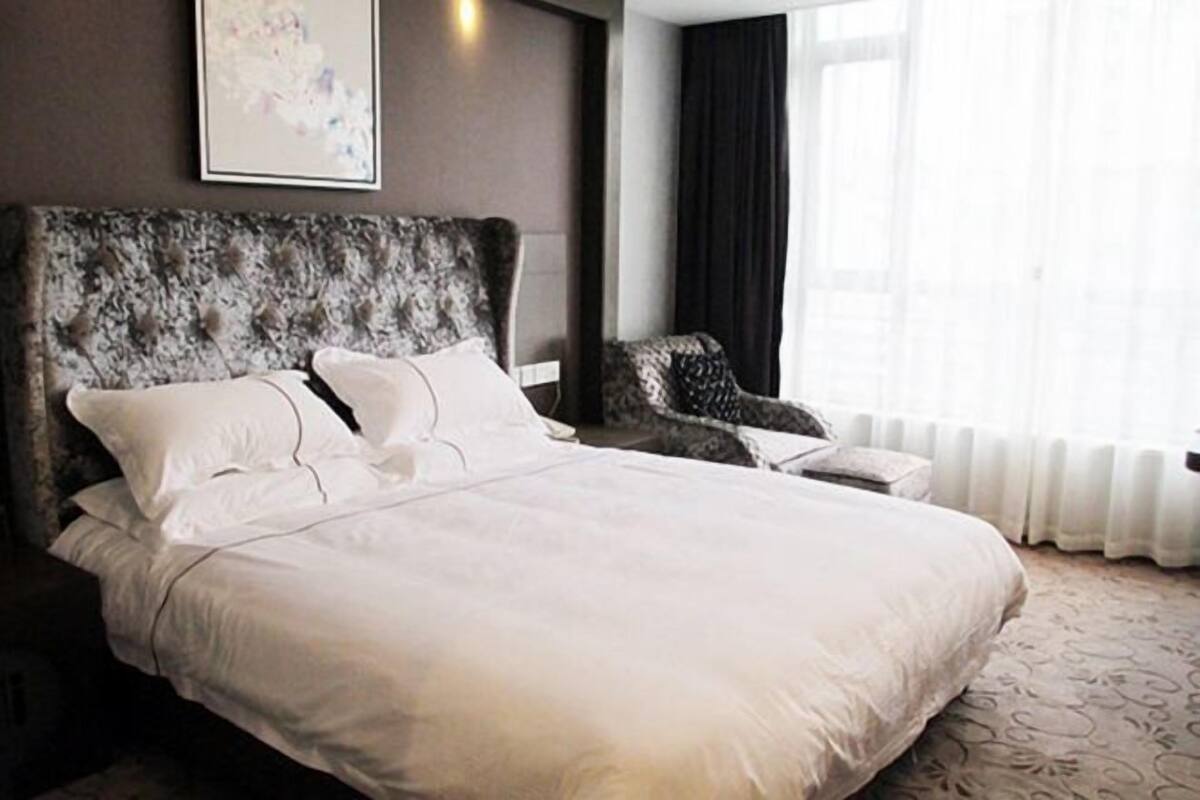 A large bed with a tufted headboard, a bedside table, and a chair.