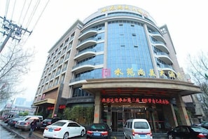 Ein mehrstöckiges Hotel mit geschwungener Fassade, großen Fenstern und einem markanten Eingang mit Beschilderung.