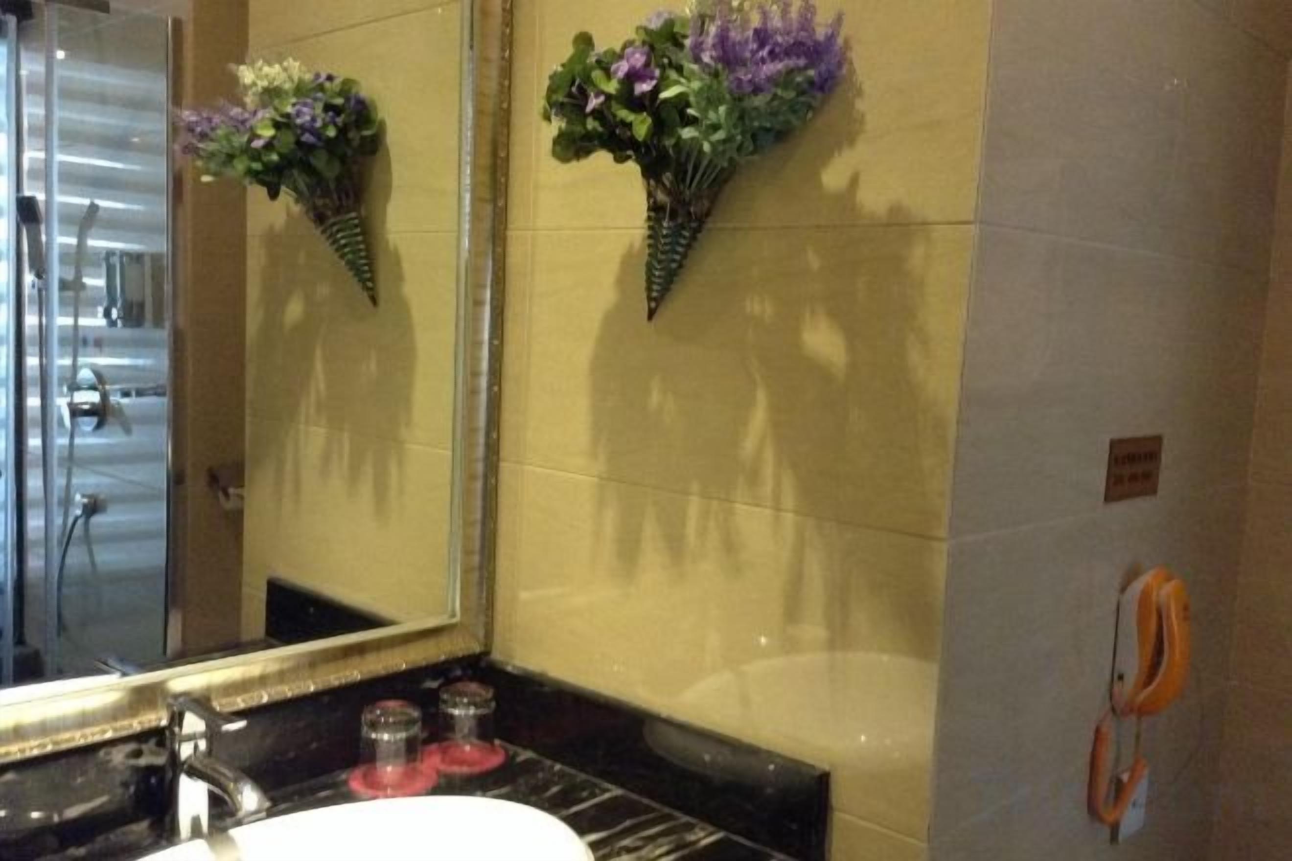 A bathroom with a large mirror, a sink, and a wall-mounted towel rack.