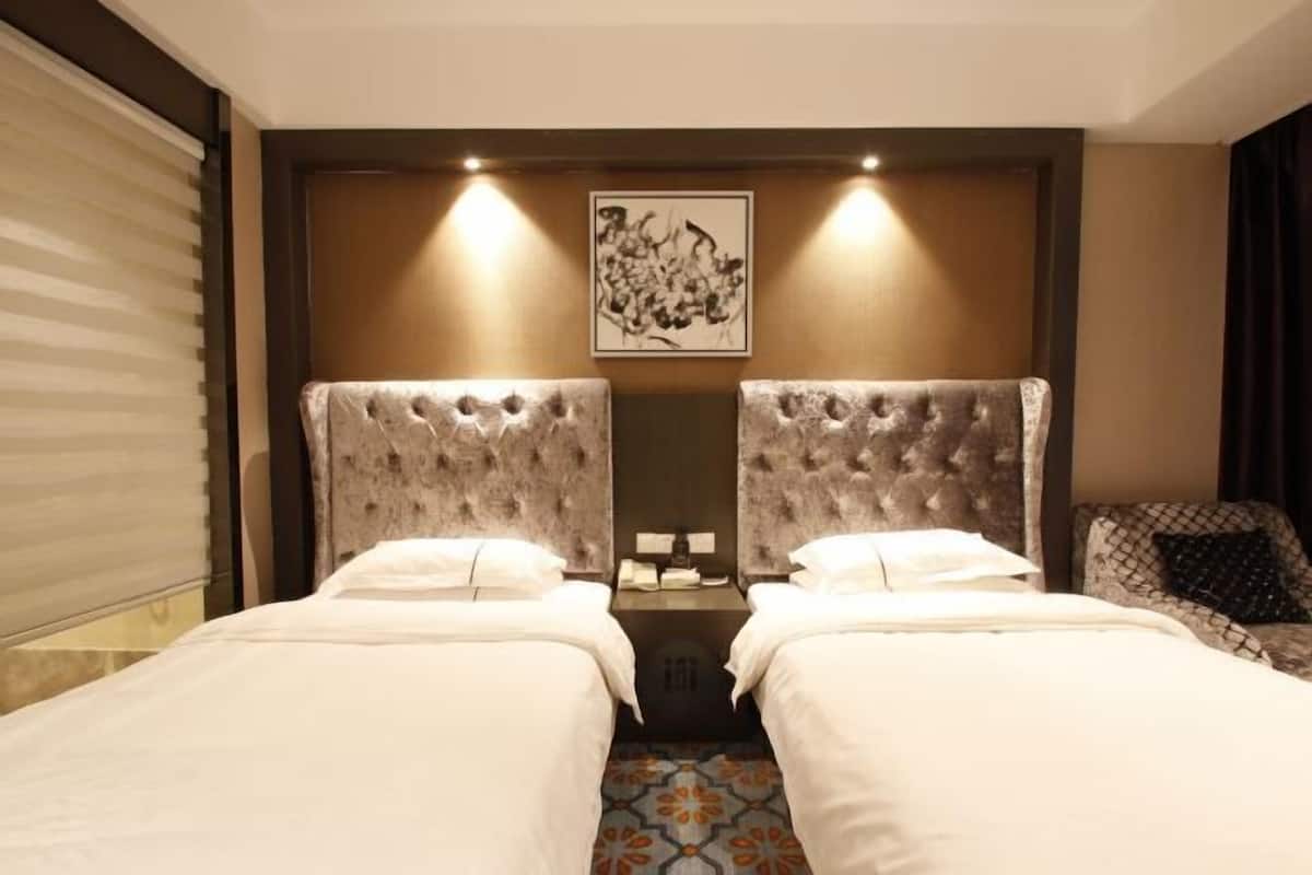 A hotel room with two beds, a large mirror, and a framed artwork on the wall.