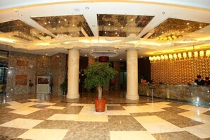 A lobby with a checkered floor, a reception desk, and a large plant in the center. - Shuiyuan Shangmei Hotel (Bengbu)