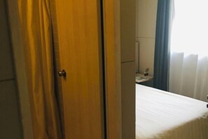 A hotel room with a bed, a wooden door, and a window with curtains. - Jinjiang Inn (Shanghai Maotai Road) (Shanghai)