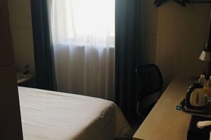 A hotel room with a bed, a desk with a kettle, and a chair. - Jinjiang Inn (Shanghai Maotai Road) (Shanghai)