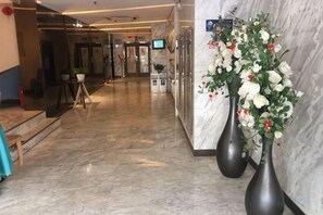 A hotel lobby with marble flooring, a reception desk, and two large vases with flowers. - Jinjiang Inn (Shanghai Maotai Road) (Shanghai)