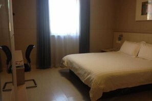 A hotel room with a bed, a desk, a chair, a nightstand, and a window with curtains. - Jinjiang Inn (Shanghai Maotai Road) (Shanghai)