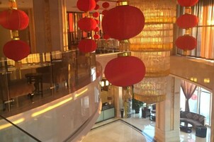 A hotel lobby with a glass railing, red lanterns, and a chandelier.