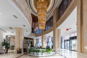 A spacious lobby with a grand chandelier, marble flooring, and a central plant arrangement. - Panshan Yinlong Hotel (Panshan)