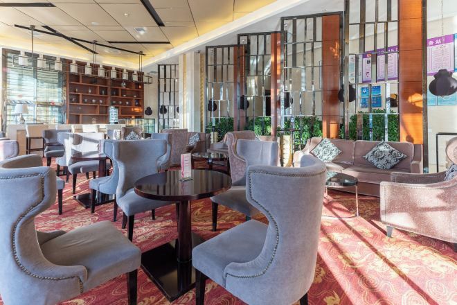A hotel lobby with seating areas, a reception desk, and decorative elements.