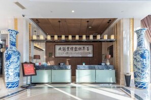 A reception area with a reception desk, two seating areas, and a large sign with Chinese characters. - Panshan Yinlong Hotel (Panshan)