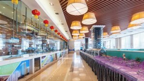 Un hall d’hôtel moderne avec un long comptoir d’accueil, des cloisons en verre et un sol ciré.