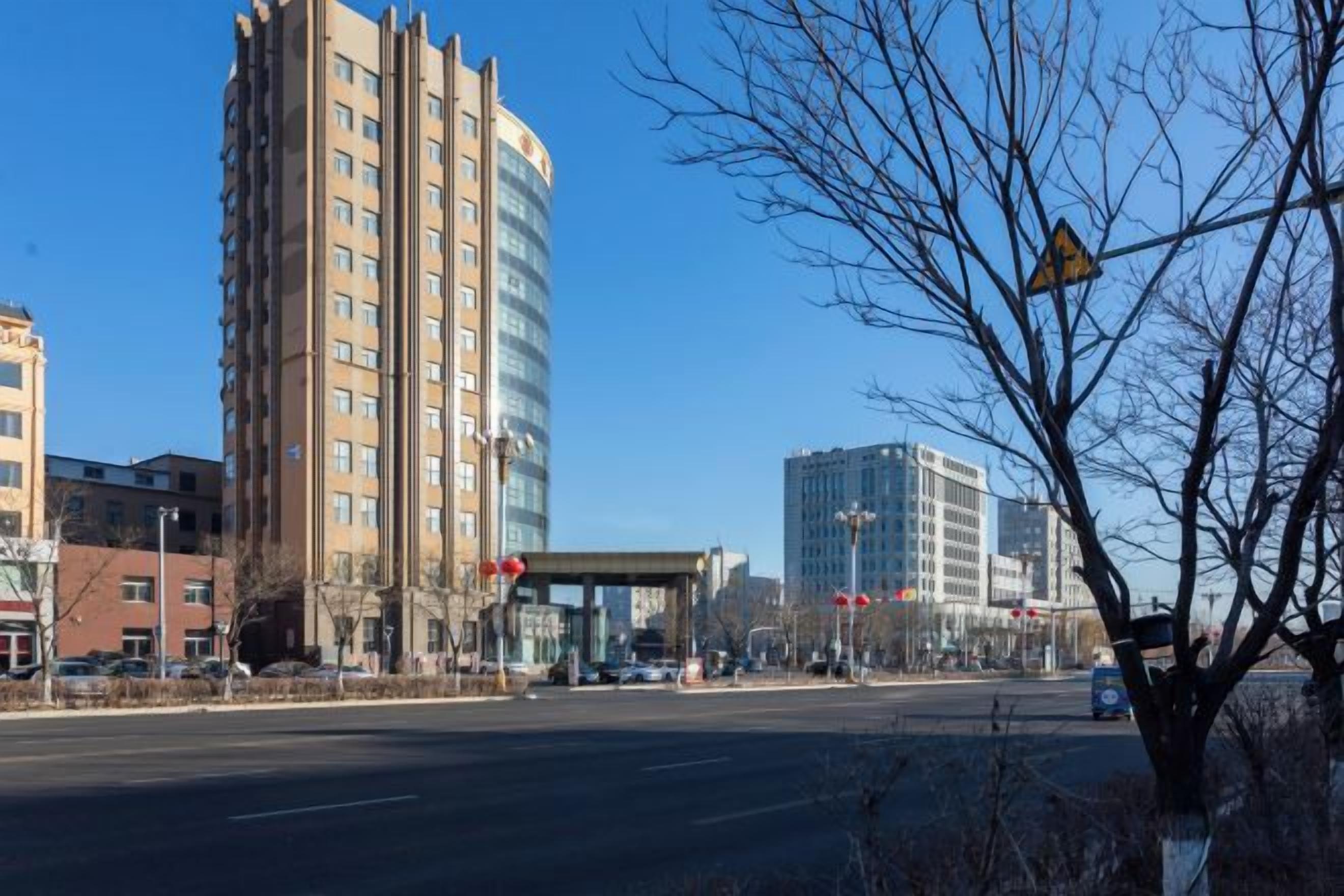 A multi-story building with a modern design, located near a road with a pedestrian crossing.