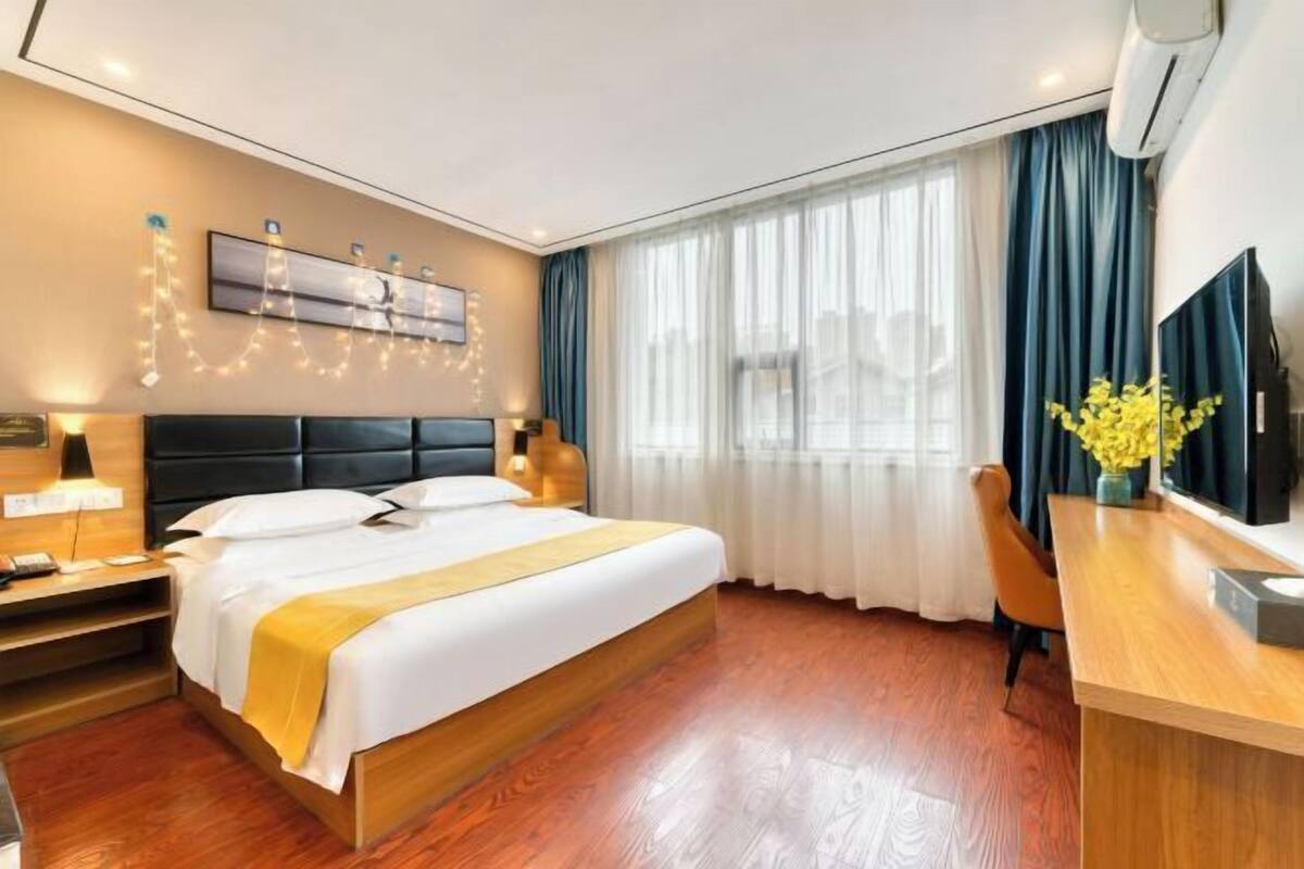 Una habitación de hotel con cama, mesita de noche, lámpara y escritorio con silla.