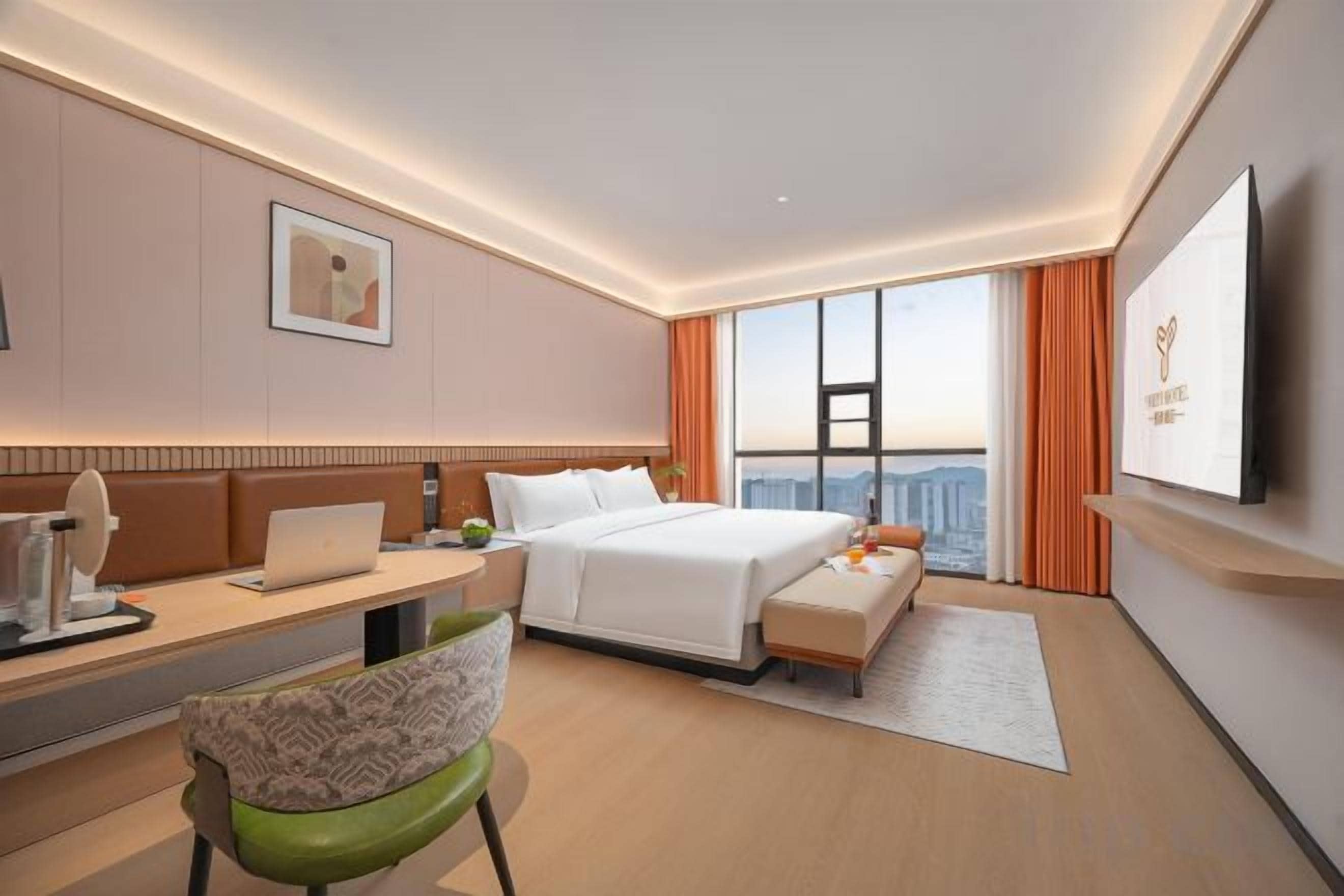 A hotel room with a bed, desk, chair, and a large window with curtains.