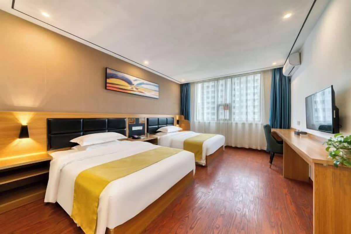 Una habitación de hotel con dos camas, un escritorio, un televisor y un cuadro en la pared.