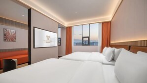A hotel room with a large bed, a desk, a chair, a TV, and a city view. - Yueyi Hotel (Huaihua Sports Center) (Huaihua)