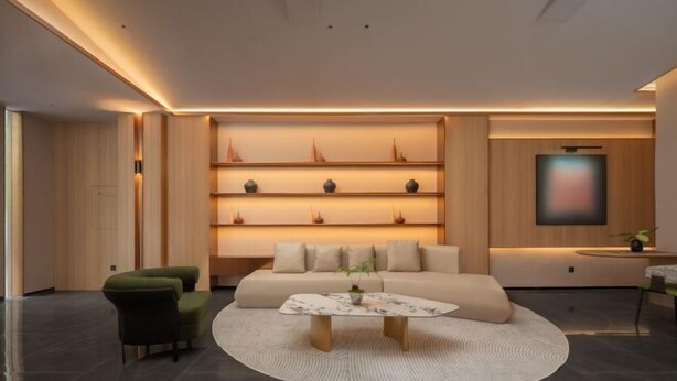 A modern living room with a sofa, a coffee table, and a wall-mounted shelf with decorative items. - Yueyi Hotel (Huaihua Sports Center) (Huaihua)