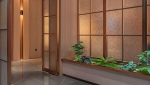 A hallway with a wooden door, a glass partition, and a plant display. - Yueyi Hotel (Huaihua Sports Center) (Huaihua)