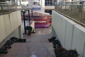Un couloir orné de plantes en pot, un escalier et une banderole.