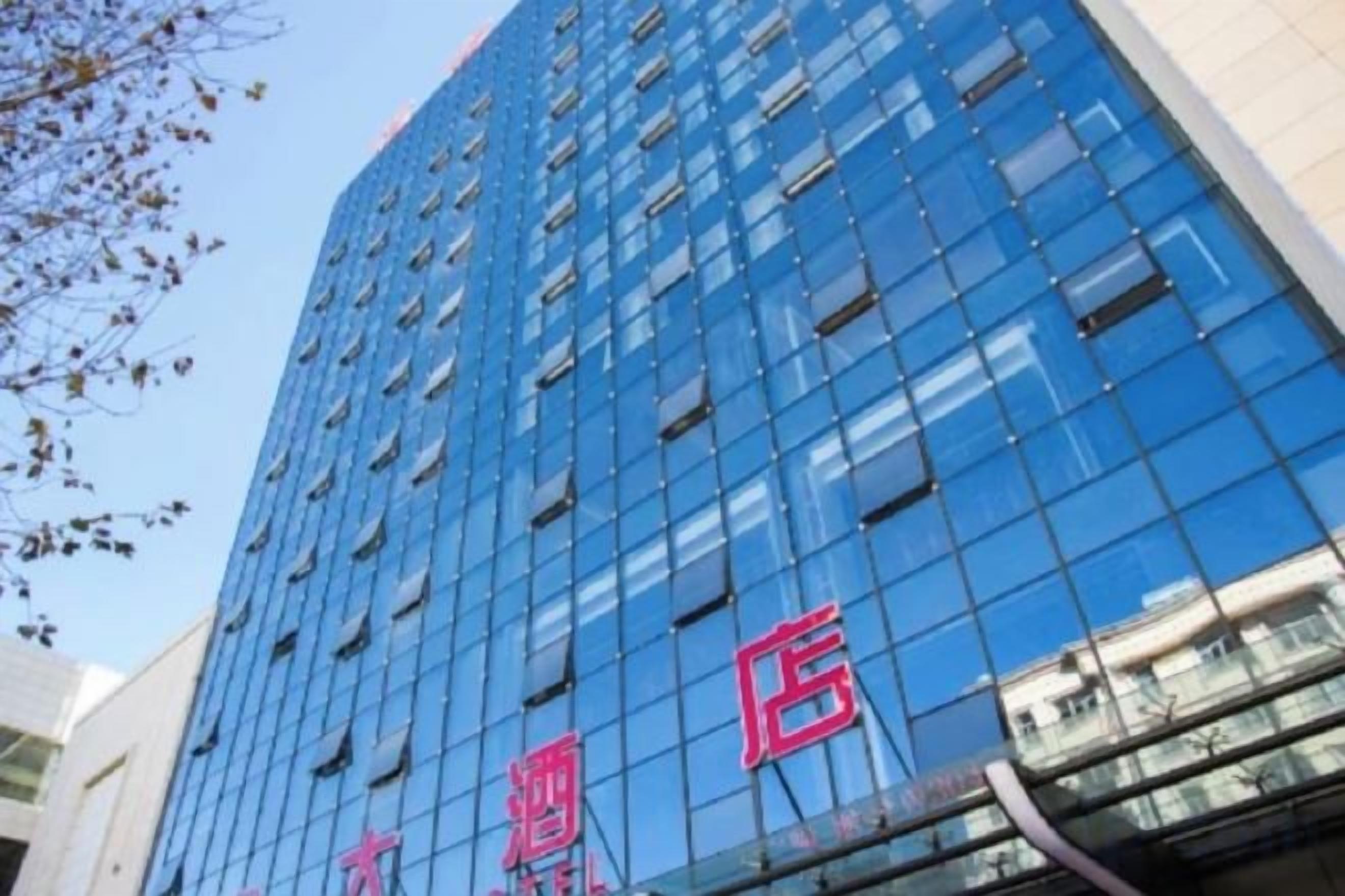 A high-rise building with a reflective glass facade and a visible sign with red lettering.