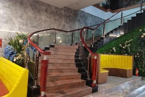 A staircase with a glass railing and a red handrail, leading to an upper level.
