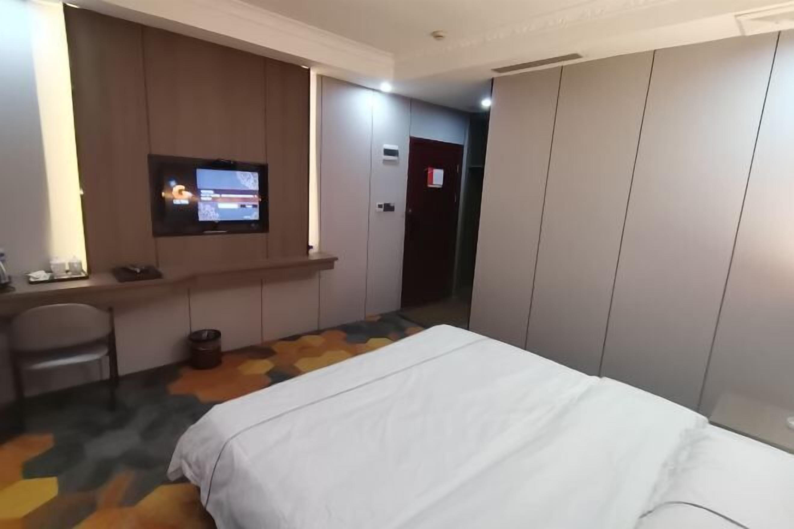 Una habitación de hotel con una cama, un escritorio con una silla, un televisor y un armario.