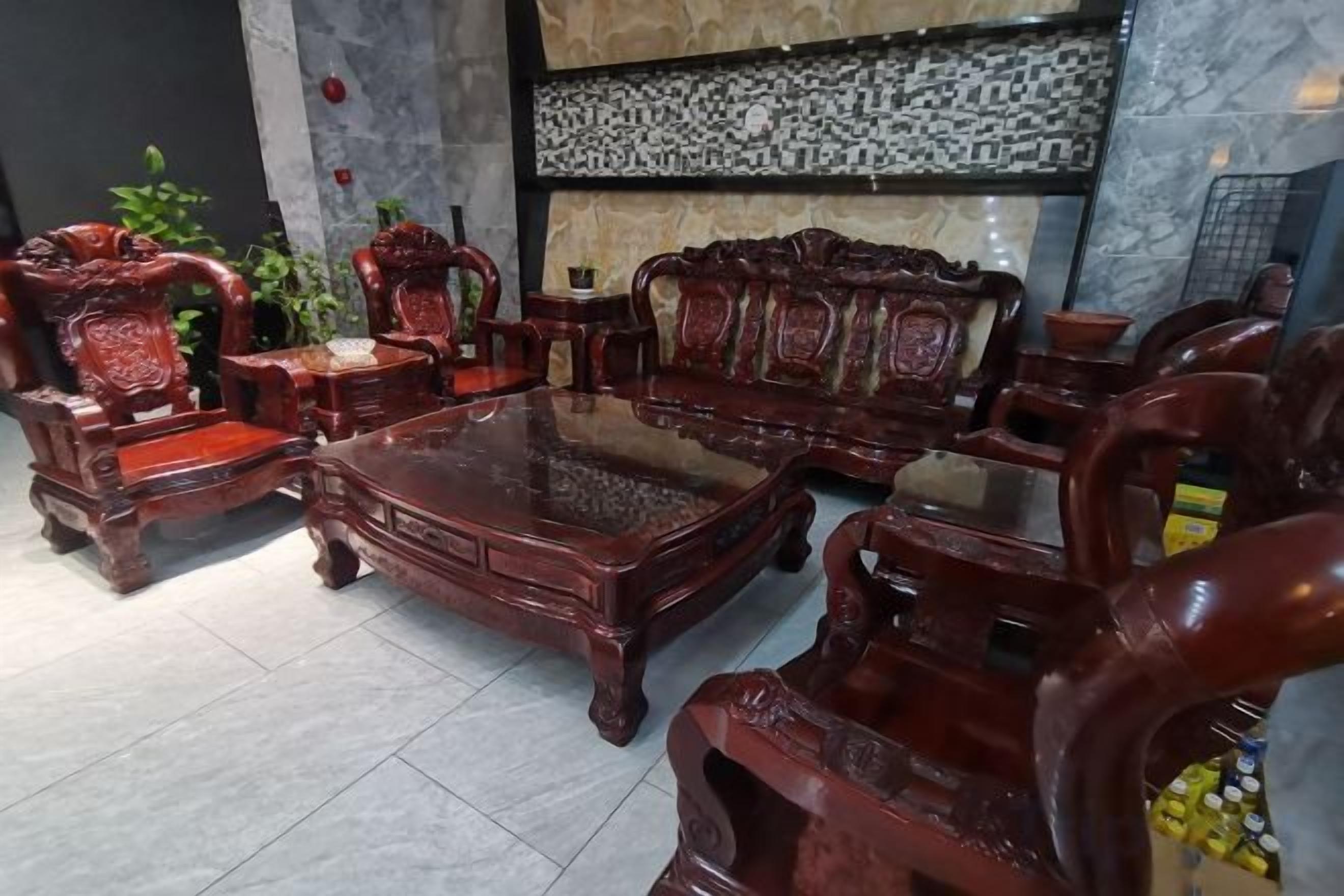 Un arredamento in legno tradizionale con un tavolino da caffè in vetro, collocato in una stanza con pavimento piastrellato e una parete decorata.