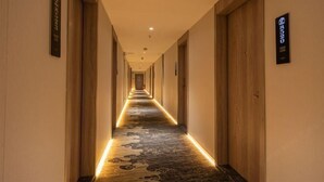 Corredor de hotel com portas de madeira e carpete estampado.