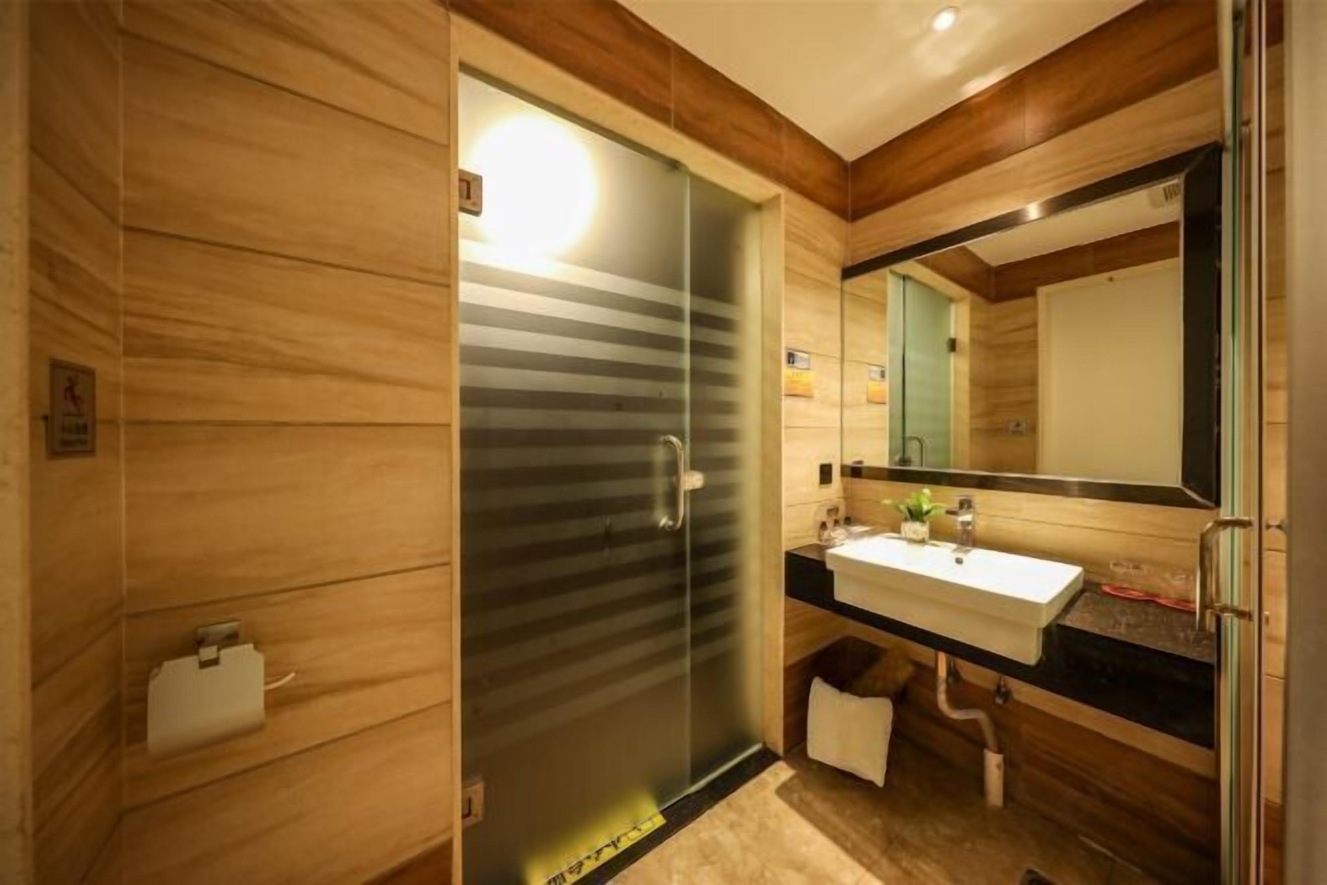 Une salle de bain moderne avec un mur en bois, une porte de douche en verre, un lavabo et un miroir.