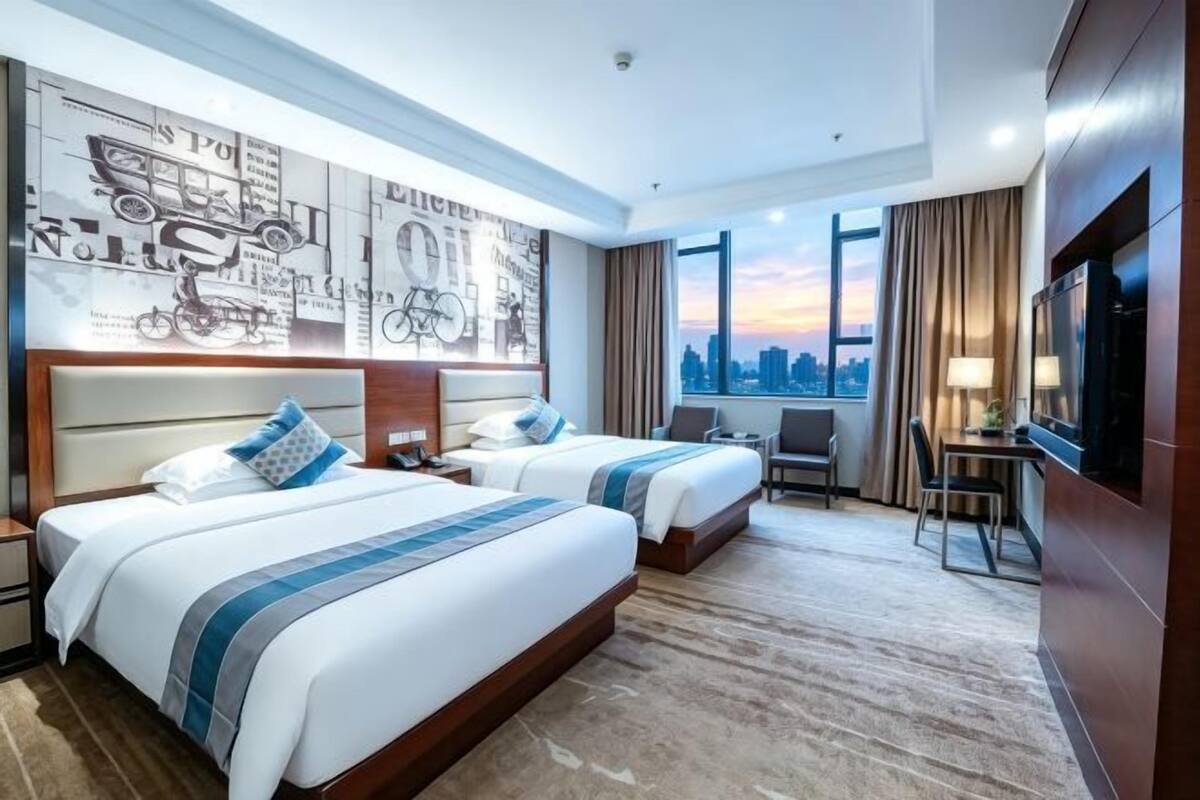 A hotel room with two beds, a city view, a desk, and a TV.