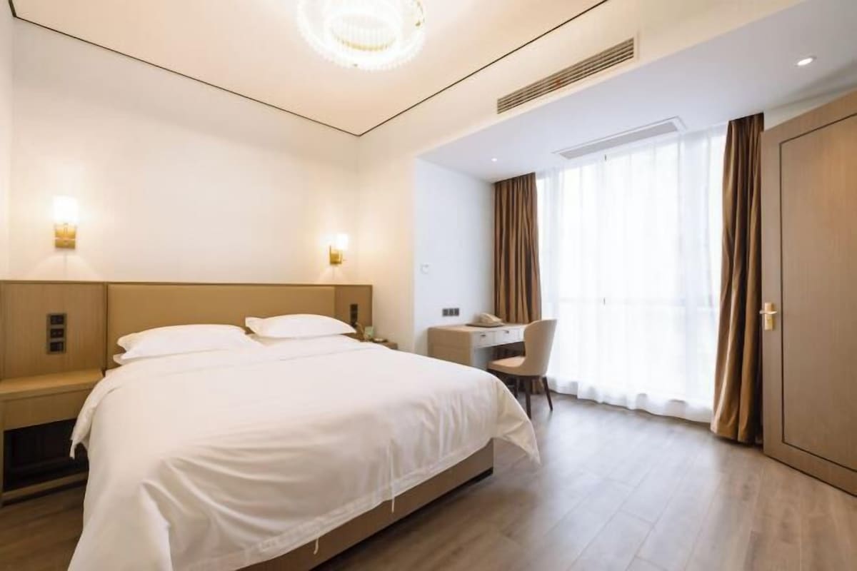 Une chambre d’hôtel avec un grand lit, un bureau et une chaise.