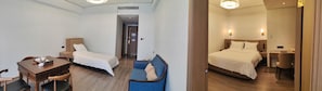 A hotel room with a bed, a desk, a chair, and a small table.