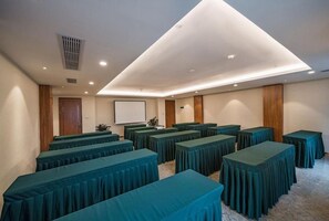 A conference room with multiple tables, a projector screen, and a whiteboard.