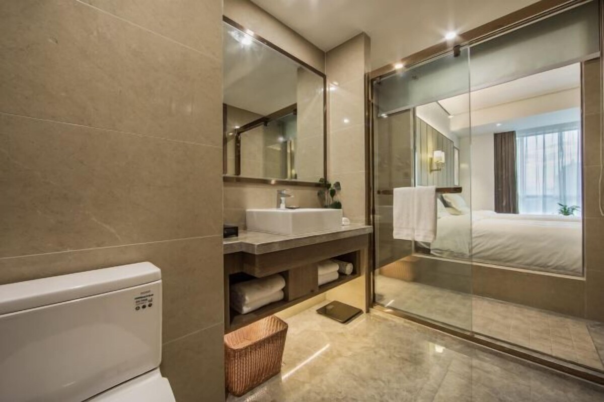 A modern bathroom with a glass shower enclosure, a white sink, and a large mirror.
