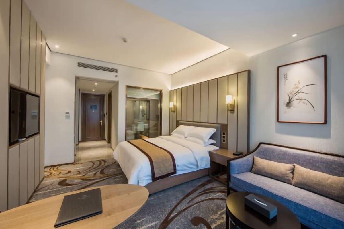 Une chambre d’hôtel moderne équipée d’un lit, d’un canapé, d’un bureau et d’une télévision.